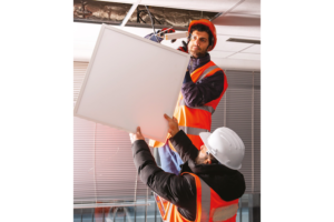 Photo de deux hommes réparant un luminaire au plafond, dans un bureau. Dossier Réparabilité